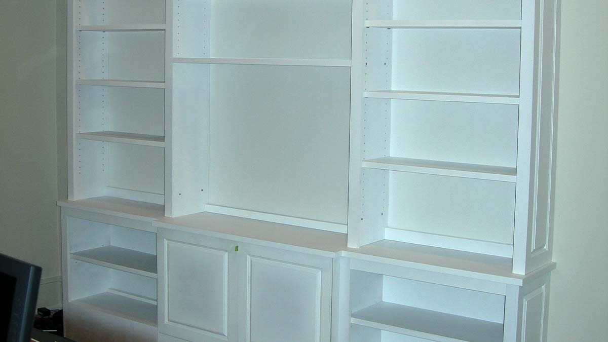 Custom built-in shelving system with open shelves and integrated lower storage in a living room