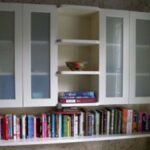 Wall-mounted display bookshelf with glass-front cabinets and open shelving in a living room.