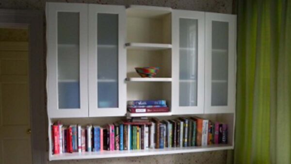 Wall-mounted display bookshelf with glass-front cabinets and open shelving in a living room.