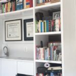 Built-in office shelving with open book storage and integrated lower cabinets in a painted finish.