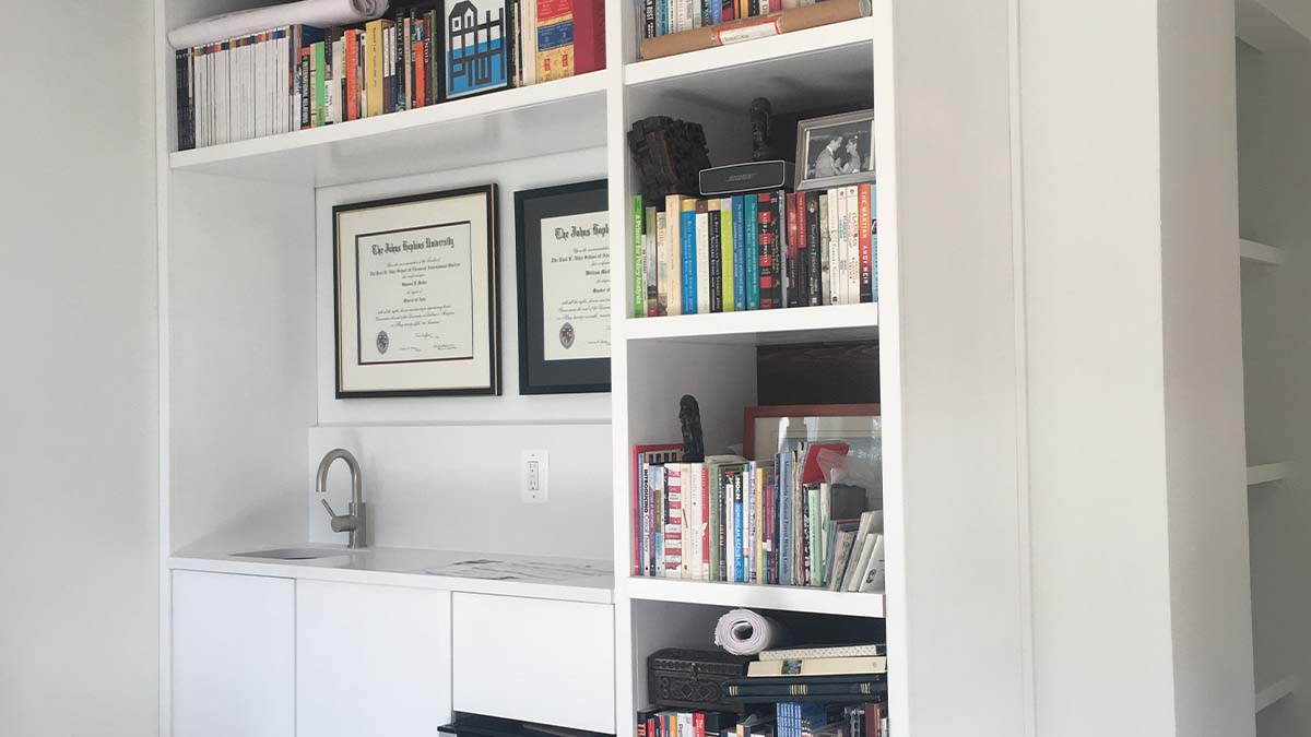 Built-in office shelving with open book storage and integrated lower cabinets in a painted finish.