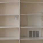 Built-in storage shelving with adjustable open shelves and painted finish in a hallway.