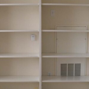 Built-in storage shelving with adjustable open shelves and painted finish in a hallway.