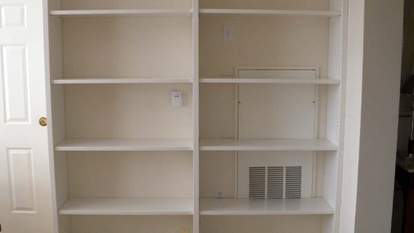 Built-in storage shelving with adjustable open shelves and painted finish in a hallway.