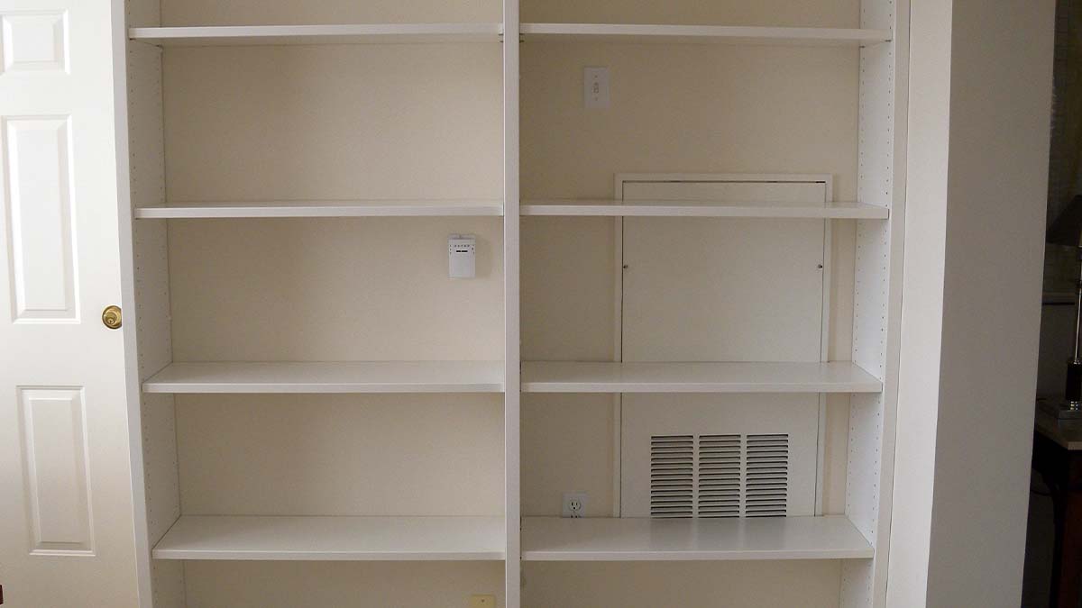 Built-in storage shelving with adjustable open shelves and painted finish in a hallway.