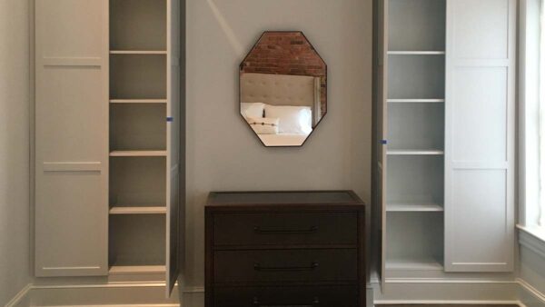 Built-in storage cabinetry with concealed cabinets and open shelving in a living room.