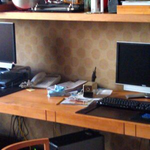 Handcrafted built-in wooden desk with integrated wall shelving and extended work surface designed as a custom multi-station workspace.