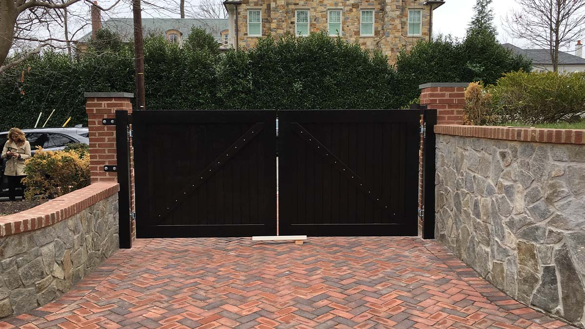 Custom wooden exterior gate with symmetrical design and dark wood finish.