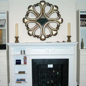 Handcrafted white fireplace mantel with built-in cabinetry, open shelving, and integrated fireplace surround forming a symmetrical living room feature wall.