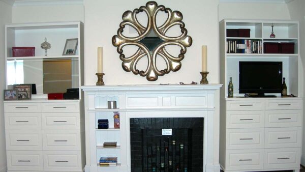 Handcrafted white fireplace mantel with built-in cabinetry, open shelving, and integrated fireplace surround forming a symmetrical living room feature wall.