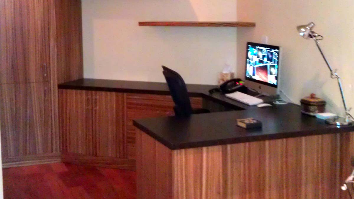 Handcrafted built-in office desk with natural wood finish, integrated cabinetry, and wraparound work surface designed for a modern workspace.