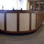 Handcrafted curved reception desk with solid wood construction, built-in configuration, and integrated front counter designed for a professional reception area.