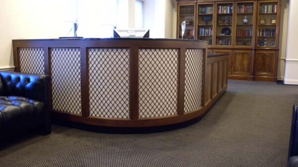 Handcrafted curved reception desk with solid wood construction, built-in configuration, and integrated front counter designed for a professional reception area.