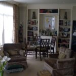 Handcrafted built-in wall shelving with integrated bar cabinet, open display shelves, and classic symmetrical design in a living room interior.