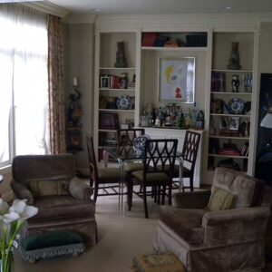 Handcrafted built-in wall shelving with integrated bar cabinet, open display shelves, and classic symmetrical design in a living room interior.