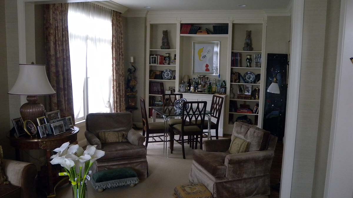 Handcrafted built-in wall shelving with integrated bar cabinet, open display shelves, and classic symmetrical design in a living room interior.