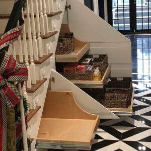 Handcrafted under-stair pull-out storage with white built-in drawers and concealed compartments designed to maximize space beneath a staircase.
